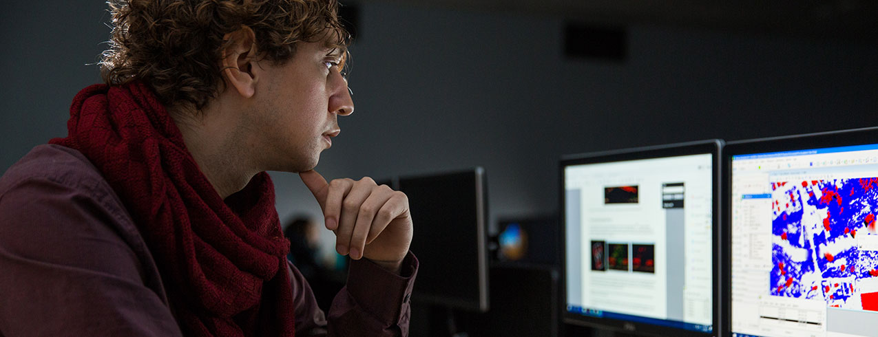 A Geographic Information Systems student is seen looking at geographical data on a computer screen. 