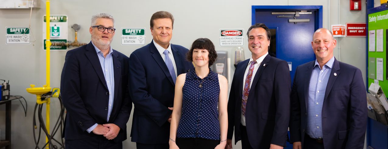 Five people stand together for a photo in a welding shop at NSCC.