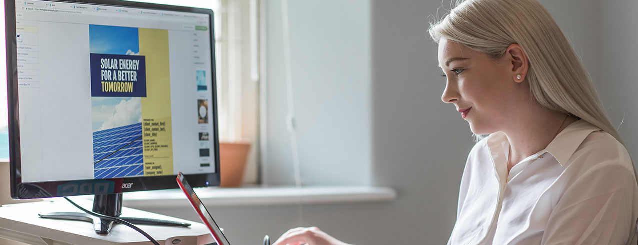 A graphic design graduate is seen working on a project on her computer laptop with a large screen projecting her work. 