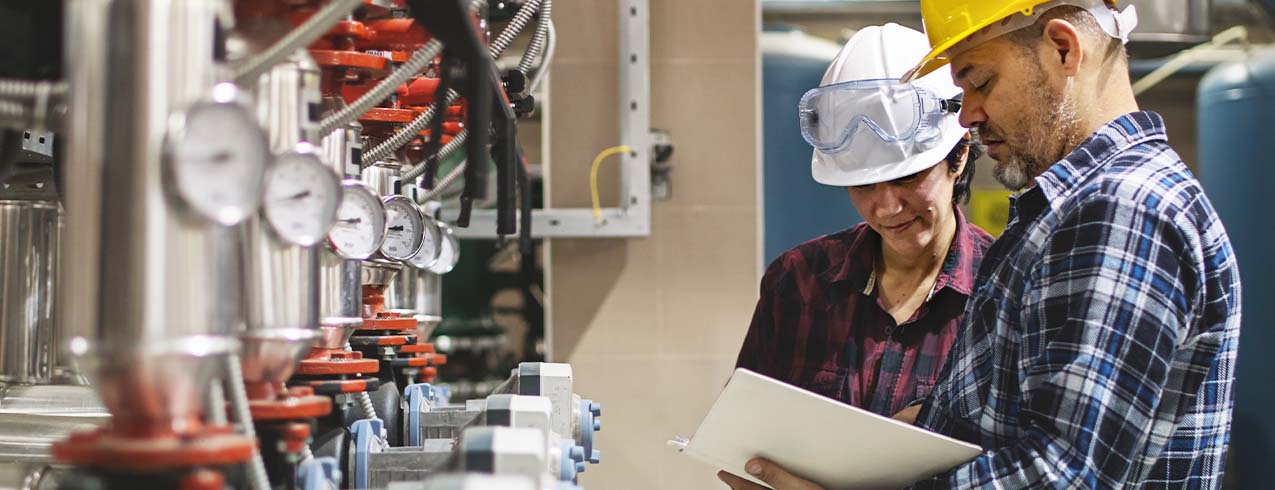 Two gas technicians work in a utility area. 