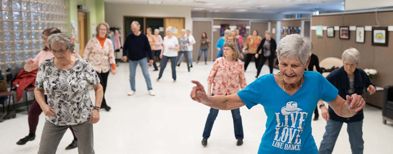 A group of people practising low-impact exercise in an indoor setting.