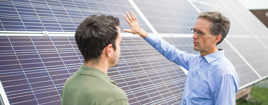 Two men standing in front of a large solar power installation for sustainable energy