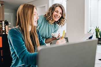 Two people look at an open laptop on a table.