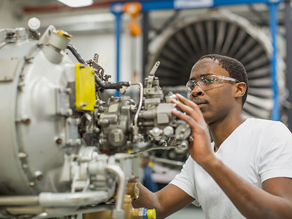 A student works on the inside of a plane's side engine.