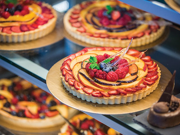 Colourful fruit tarts sitting in a display case.