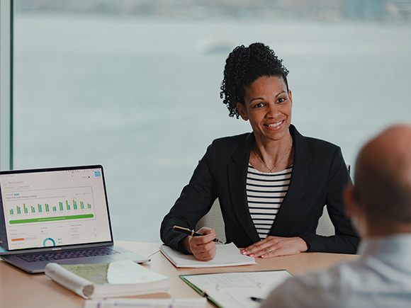 A professionally dressed woman sits at a conference table.