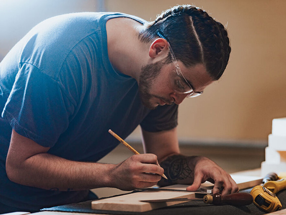 A student measures lumber on a shop table at NSCC.