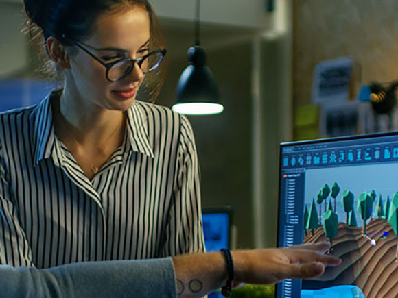 A woman in a striped shirt looks at a computer screen.