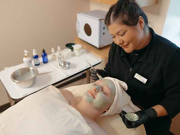 A woman receives a hot stone massage in a spa setting.