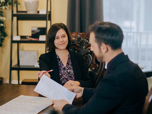 Two people sit together reviewing a document in a funeral setting.