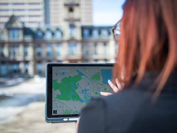 A woman looks at a map on her tablet computer while standing outside Halifax's city hall.