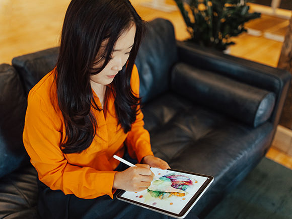 A woman uses a stylus pen to sketch a design on her tablet computer.