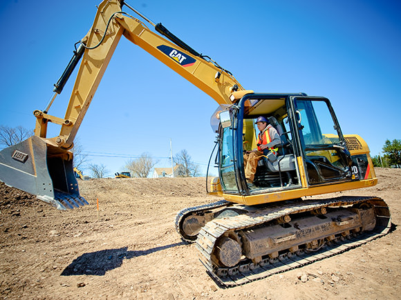 A man operates a large excavator at a construction site.