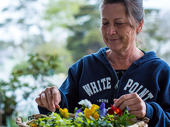 A woman tends to a pot of flowers.