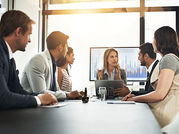 Six people gather around a meeting room table.