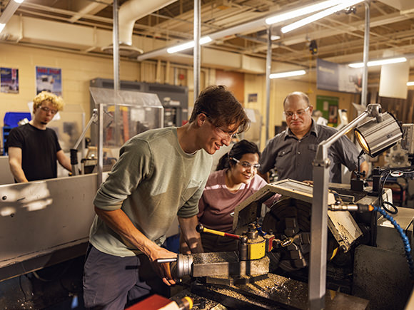 A man bends over to take a closer look at the machinery he's working with.