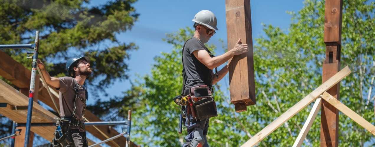 Two people building the frame of a sustainable house on a sunny day.