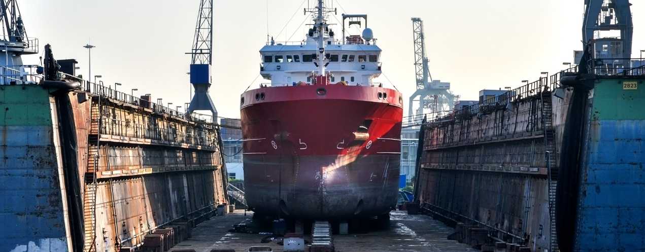 Large commercial vessel positioned inside a dry dock during maintenance operations.