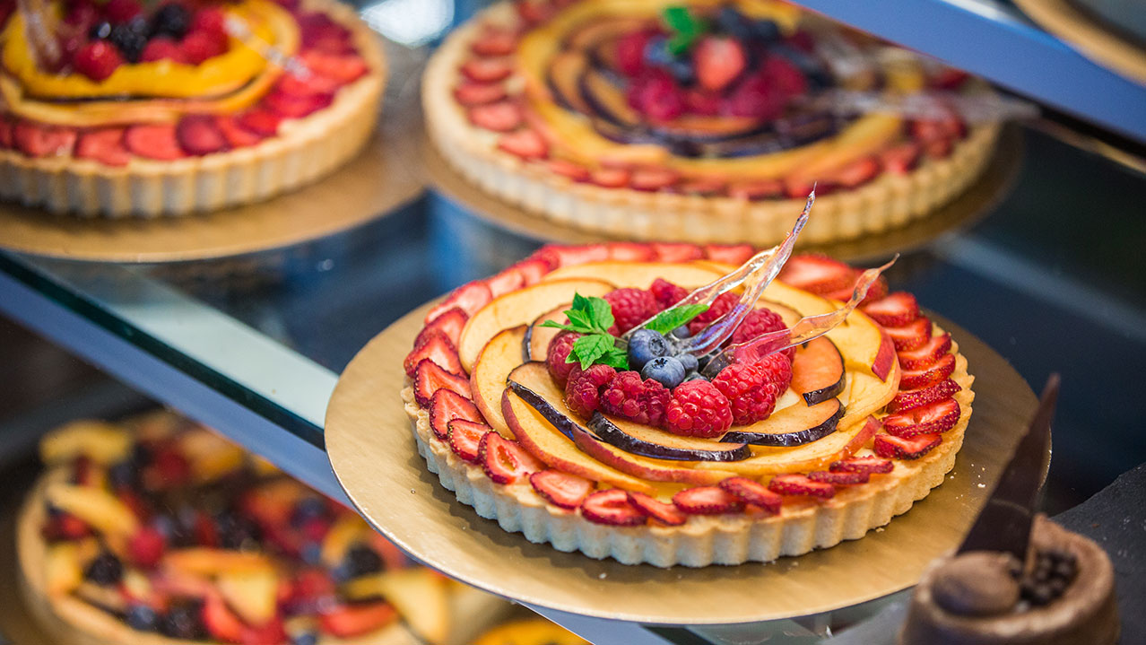Colourful fruit tarts sitting in a display case.