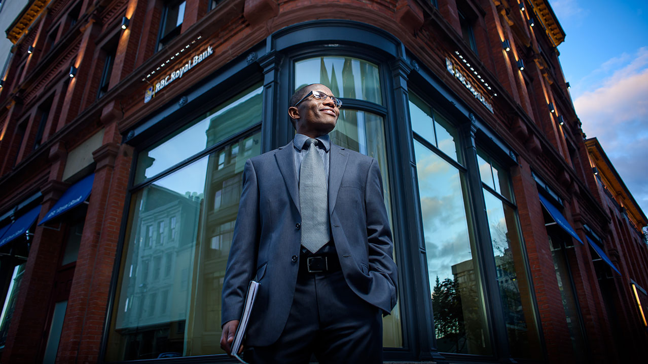 A business professional in a suit stands tall in front of a building.