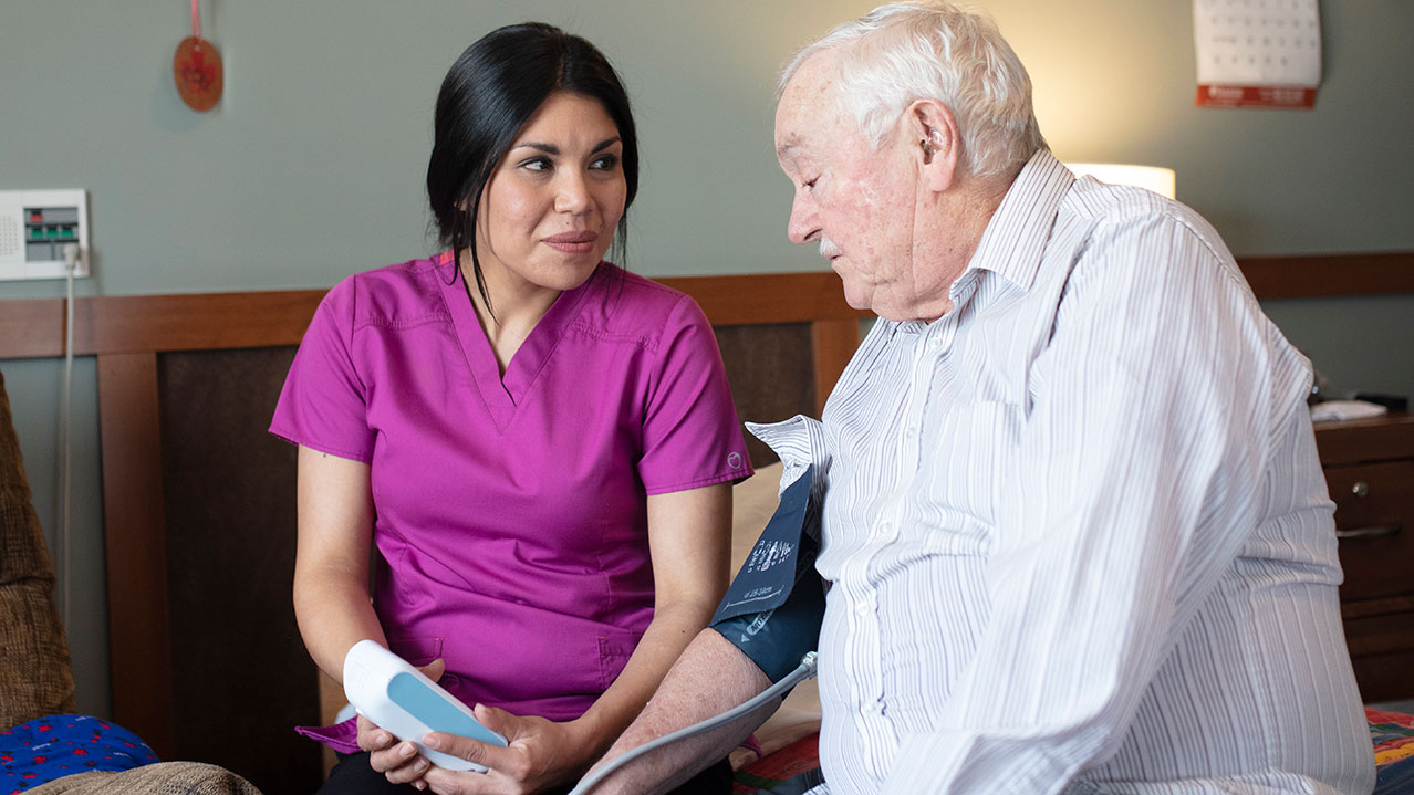 An NSCC Continuing Care grad sits with a patient and talks.