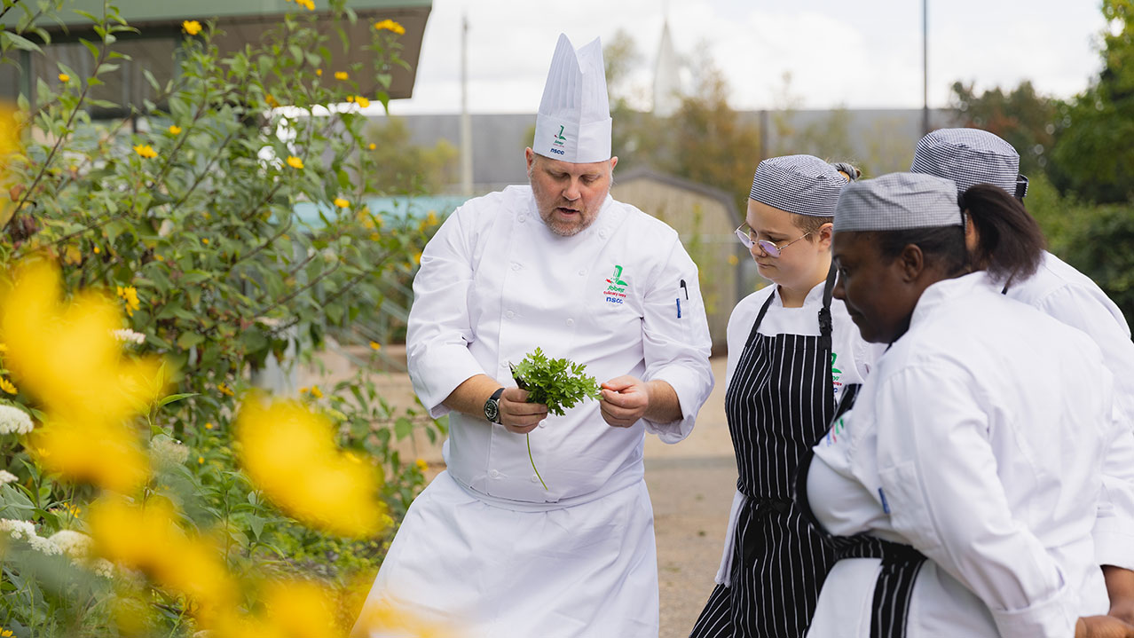 An NSCC Culinary Management instructor shows students food grown in the campus garden.