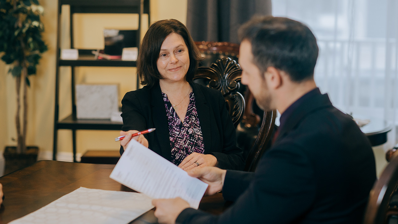 Two people sit together reviewing a document in a funeral setting.