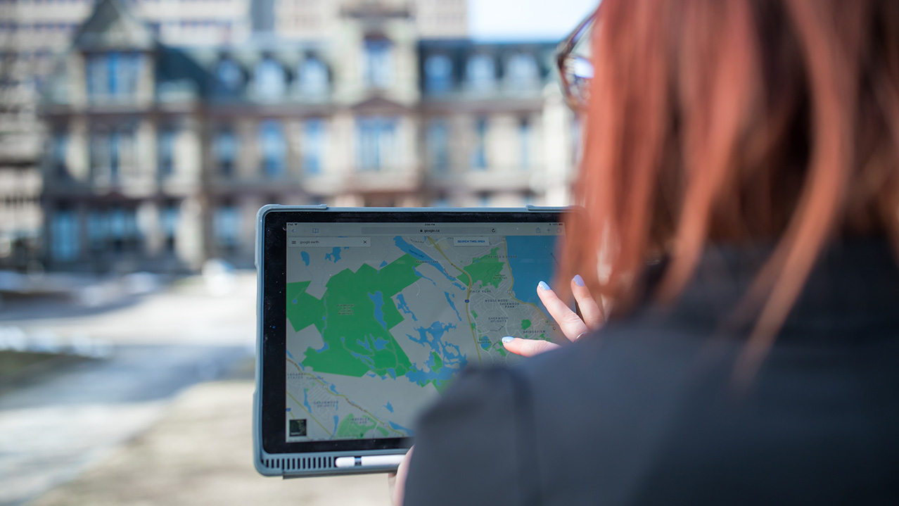 A woman looks at a map on her tablet computer while standing outside Halifax's city hall.