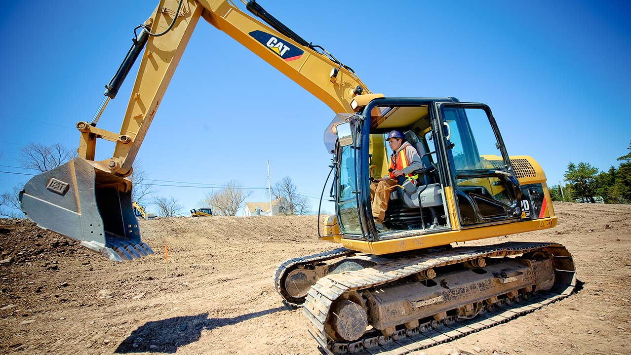 A man operates a large excavator at a construction site.