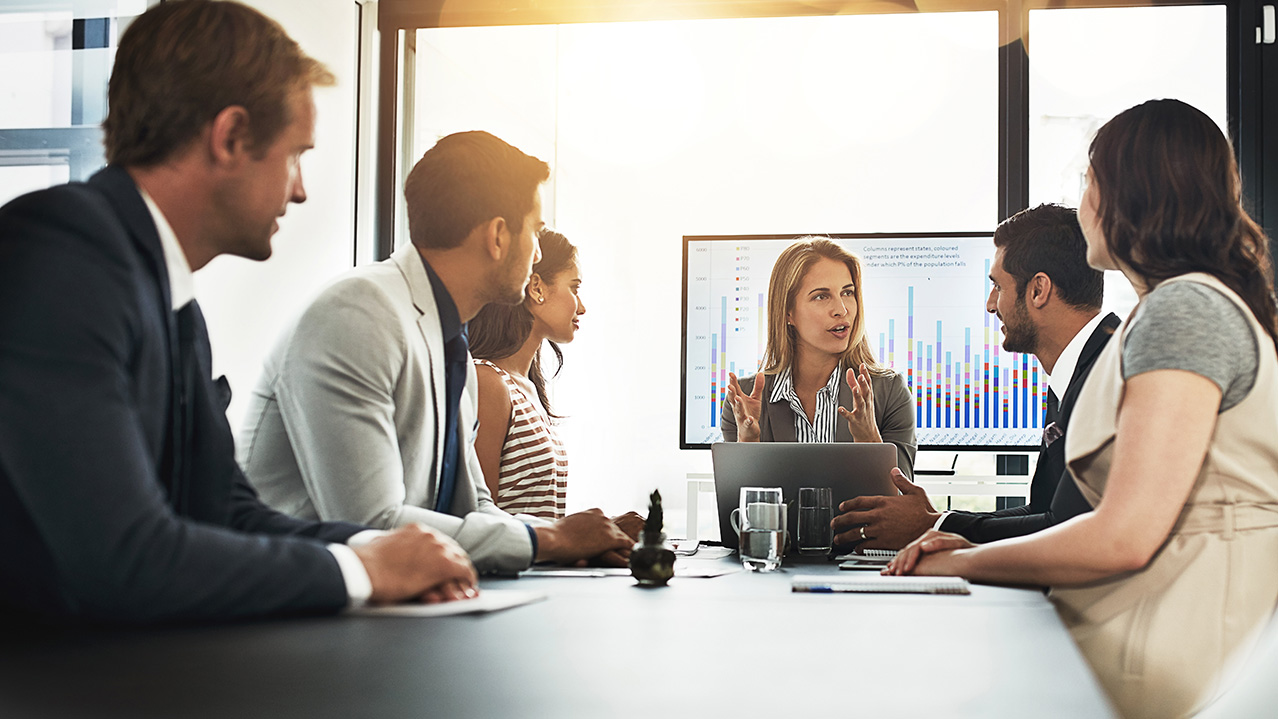 Six people gather around a meeting room table.