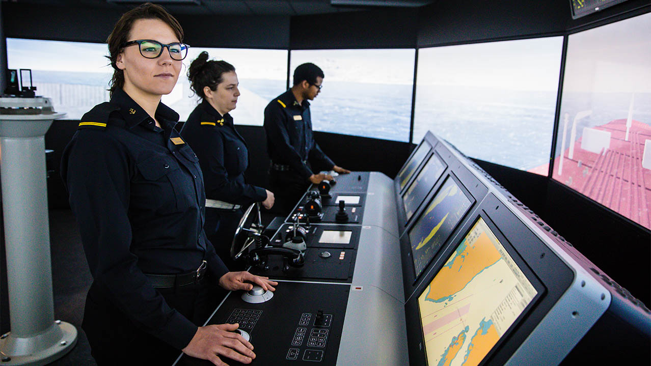 Three students in uniform practise their skills inside the Nautical Institute's marine navigation simulator.