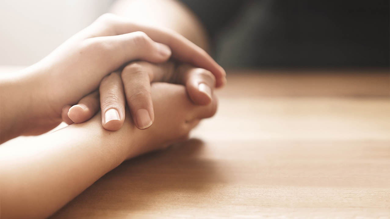 One set of hands holds another.