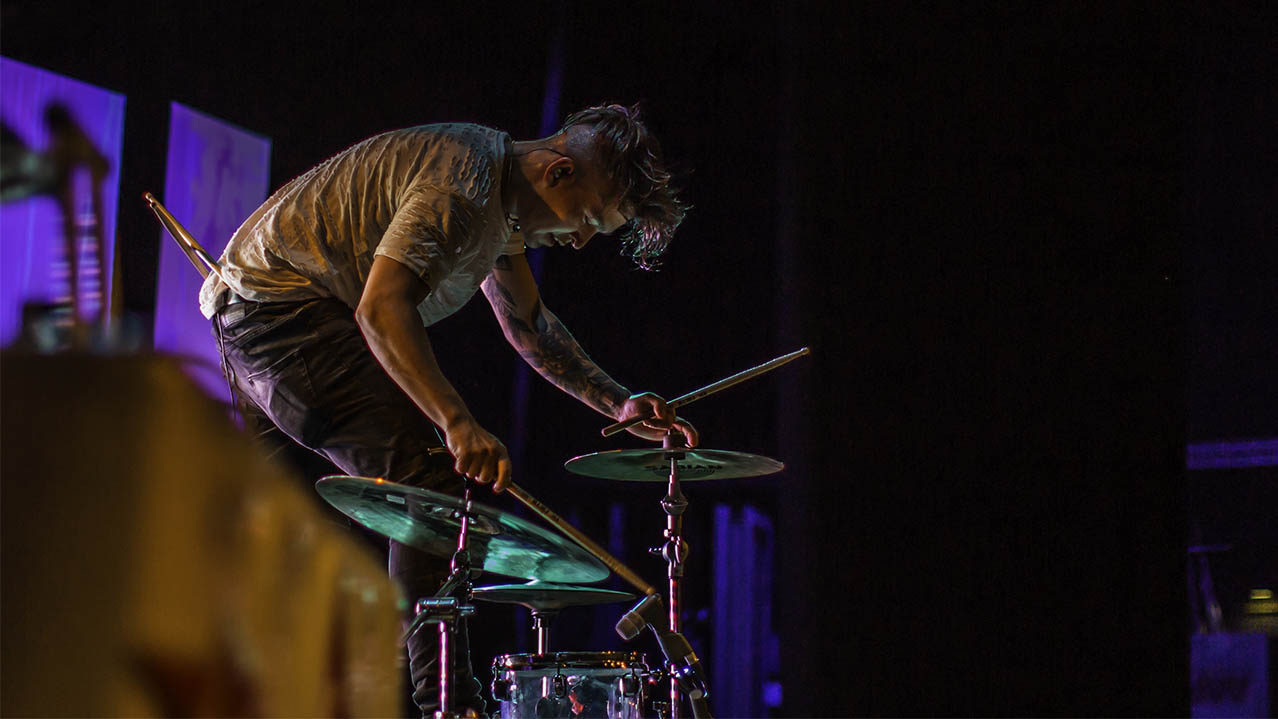 A Music Arts student playing the drums on a stage.