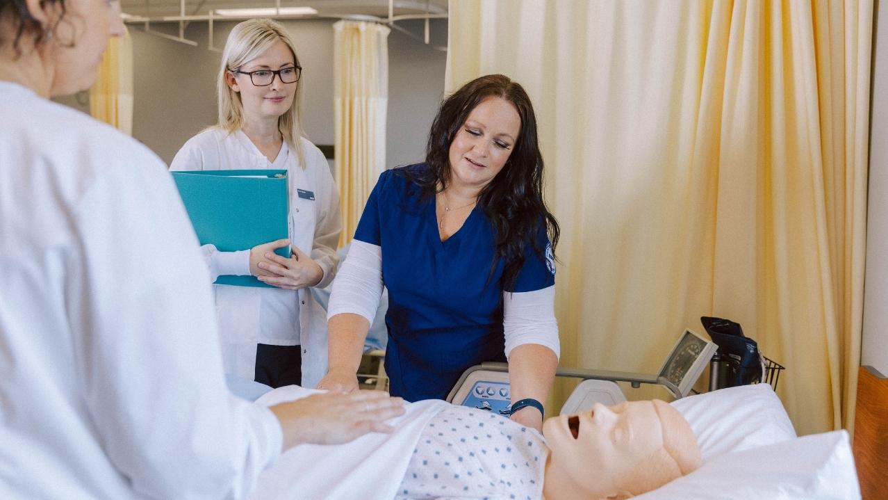 NSCC Practical Nursing student Marcia checks a mannequin simulated patient in a hospital bed in the Practical Nursing lab.