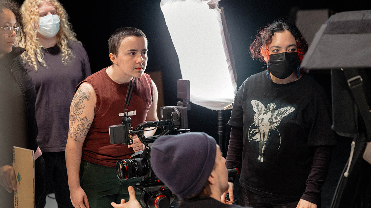 Five people stand around a camera as they work on a film set.