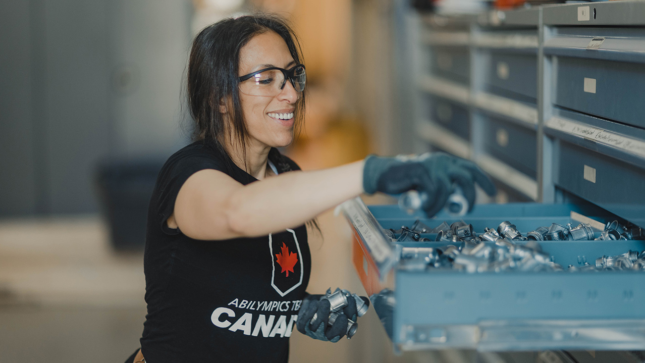 An NSCC Women Unlimited student smiles as she reaches into a drawer to look for a mechanical part.