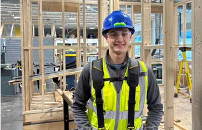 Picture of a smiling man in hard hat and protective gear at a construction site.