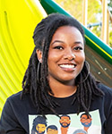 Jaden sits at the bottom of a slide and smiles at the camera.