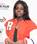 Juliet poses in front of a backdrop on a red carpet at a film event.