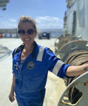 Tenille poses on the deck of a large ship on a sunny day.