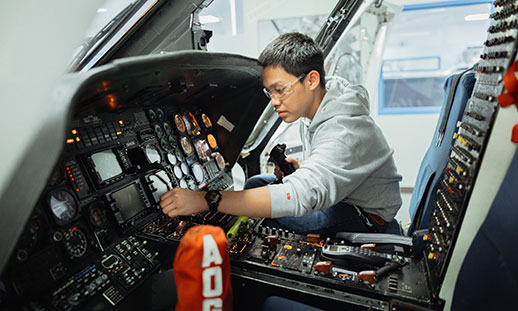 An aircraft maintenance diploma student works on the the instruments of an airplane inside of the aircraft.
