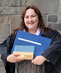 A photo of Brittany in graduation gown holding her diploma.