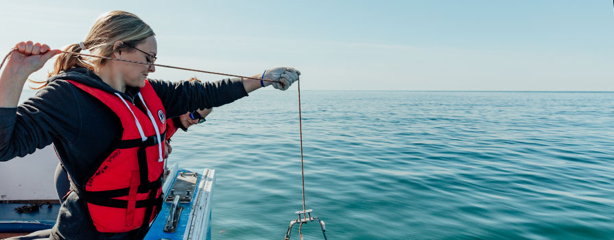 Two woman on a boat collect water samples. 