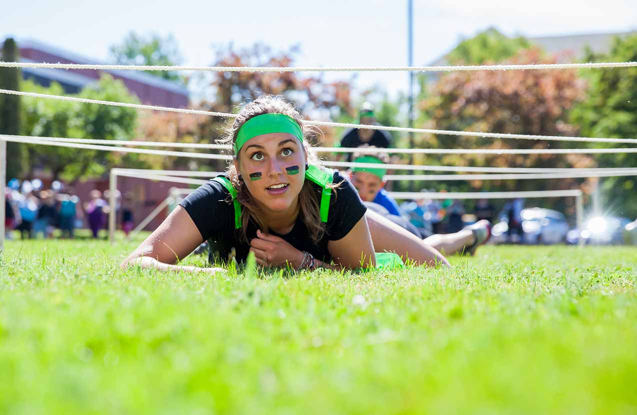Student on ground smiling during a relay race.