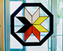 An 8-pointed Mi’kmaw star made of stained glass hangs in a window.