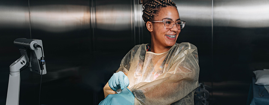 Woman with braces smiling and putting on scrubs.