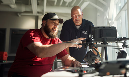A student and instructor look at technical equipment together in a classroom setting.