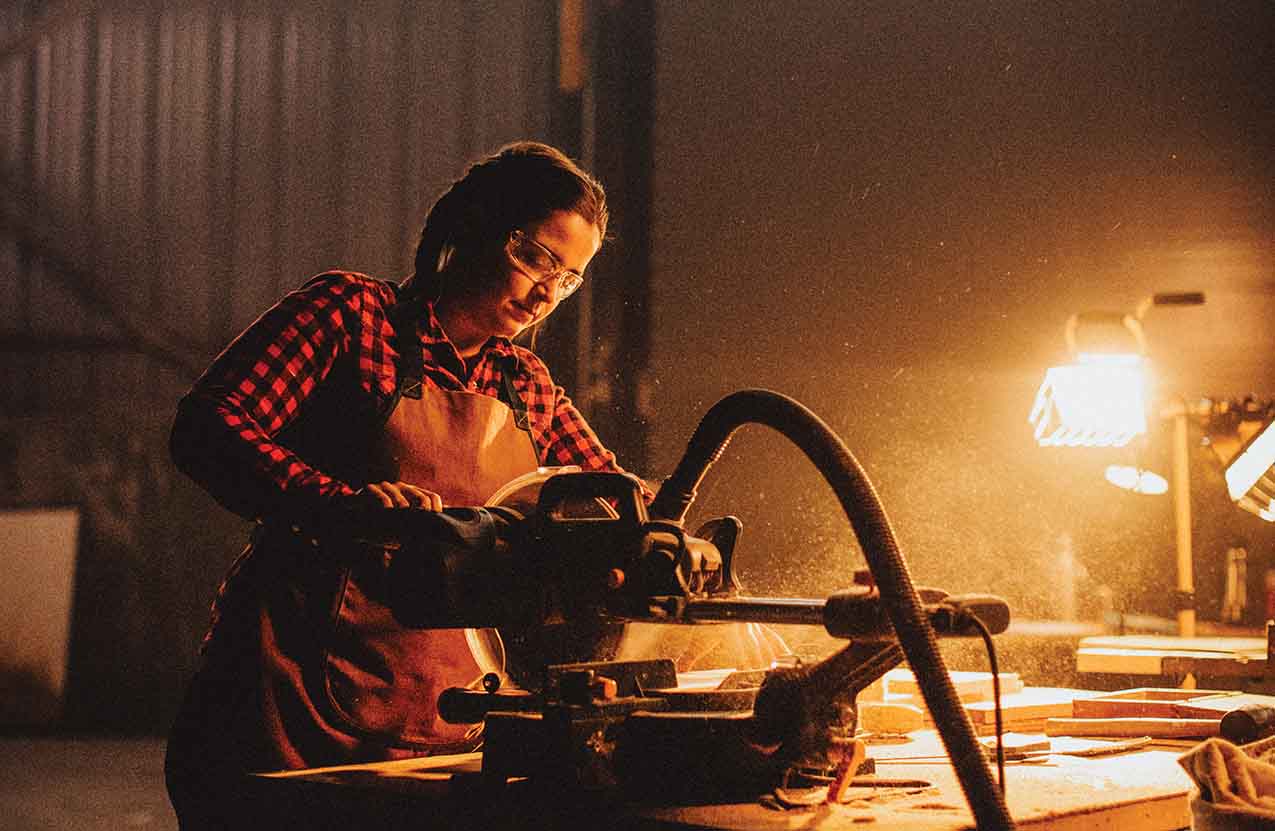 An Indigenous woman works on a woodworking project inside a shop.