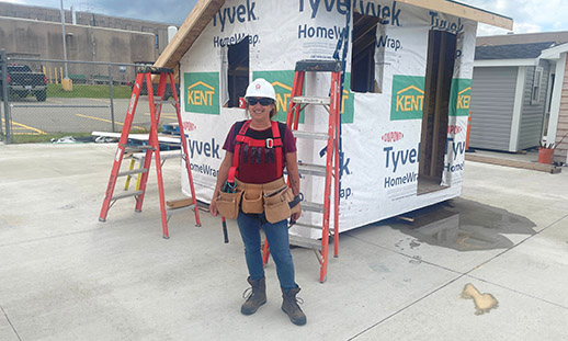 Melanie stands in front of an under construction shed.