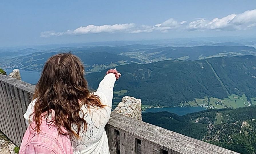 Dakota Sibbley points toward scenic mountains in Austria.